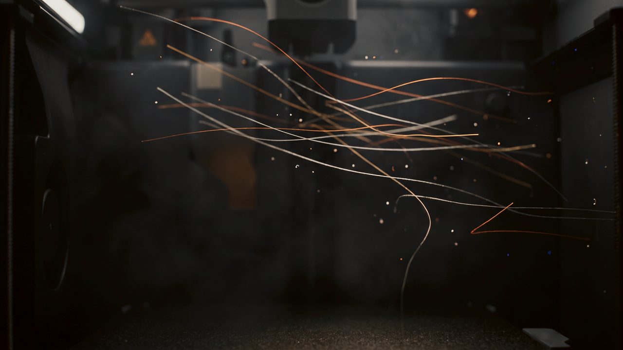 Threads of light drift through a dark printer chamber
